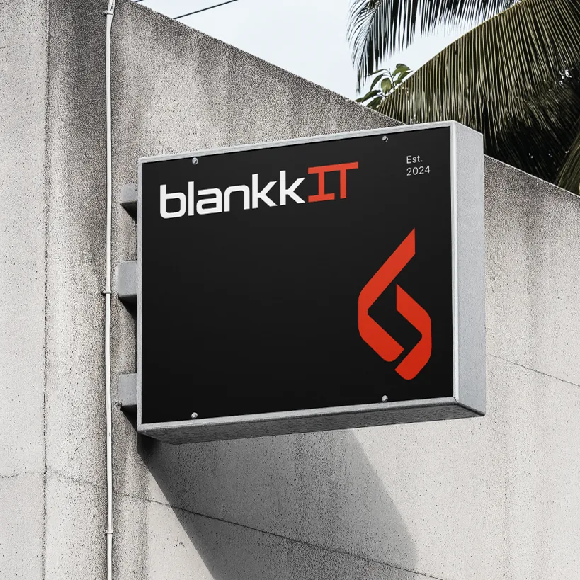 Schwarzes blankkIT-Firmenschild mit weiß-rotem Logo an einer Betonfassade.